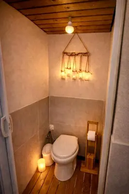 a bathroom with a toilet and lights on the wall at Maison bord de plage avec patio extérieur aménagé in Puerto de Sagunto