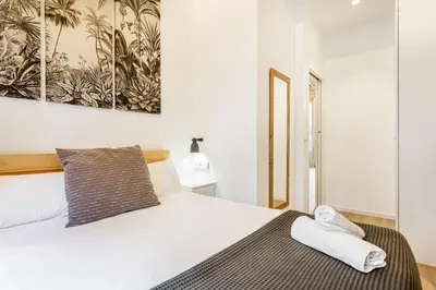 a white bedroom with a bed with a towel on it at AIRE Holidays Valencia in Valencia