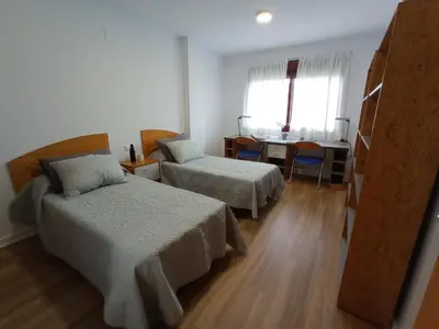 a hotel room with two beds and a desk and a table at MiCampus Burjassot 1 Student Residence in Burjasot