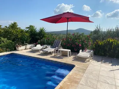 a pool with two chairs and a red umbrella at Casa Ramona in Valencia