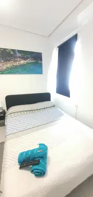a bed with a pair of blue slippers on it at Céntricas, Tranquilas y Acogedoras Habitaciones de Matrimonio en Vivienda Compartida in Valencia