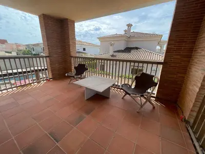 a patio with two chairs and a table on a balcony at Villa con barbacoa para familias in Mareny Blau