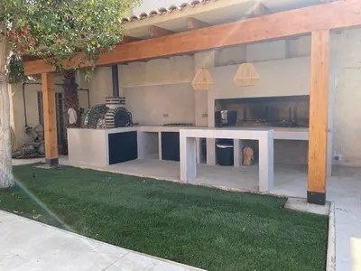 an outdoor kitchen with a white table in a backyard at Villa con barbacoa para familias in Mareny Blau