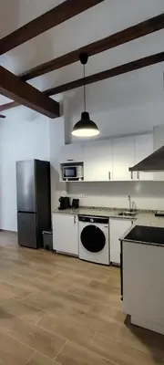 a large kitchen with white cabinets and a refrigerator at Beachside apartment in Valencia