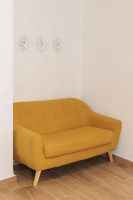 a yellow couch against a white wall with flowers on the wall at Apartamento Estilo Rustico Buñol - ELPATIO- in Buñol