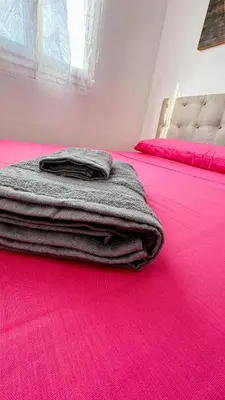 a stack of towels sitting on top of a pink bed at Kmilo in Valencia