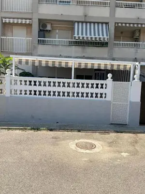 a white fence in front of a building at Apartamento Canet de Berenguer con terraza exterior a 100m de la playa in Canet de Berenguer