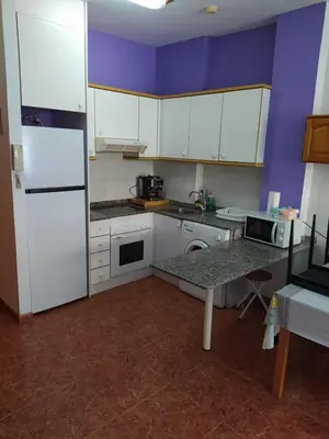 a kitchen with white appliances and a purple wall at Apartamento Canet de Berenguer con terraza exterior a 100m de la playa in Canet de Berenguer