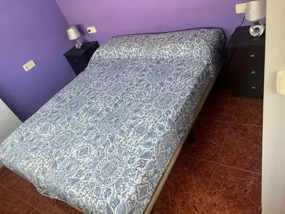 a bed with a blue comforter in a bedroom at Apartamento Canet de Berenguer con terraza exterior a 100m de la playa in Canet de Berenguer
