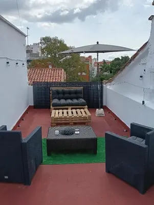 a patio with a couch and an umbrella on a roof at El Molino 2 Buñol Apartamento in Buñol