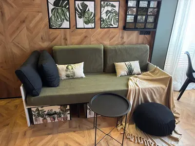 a living room with a green couch with pillows at Farnals Playa Valencia in Masalfasar