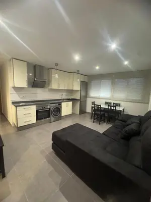 a living room with a black couch and a kitchen at UIM Mediterraneo Hispanidad 4 Wifi in Puerto de Sagunto