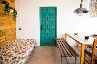 a green door in a room with a table and a bench at Bonita casa cueva con jacuzzi in Paterna
