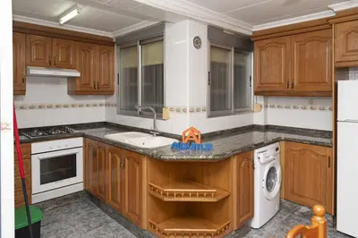 a kitchen with wooden cabinets and a sink and a dishwasher at Pasaje Alzira 4B, 1-3 in Cullera