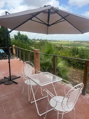 a patio with a table and chairs and an umbrella at Casa Perenchiza in Chiva