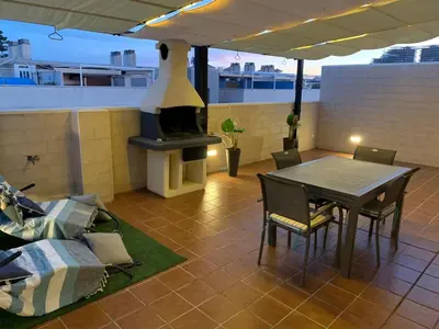 a patio with a table and a fireplace on a roof at Encantador Apartamento dúplex con vistas al mar in Canet de Berenguer