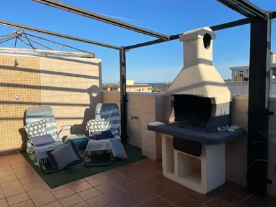 a patio with two chairs and a fireplace on a roof at Encantador Apartamento dúplex con vistas al mar in Canet de Berenguer