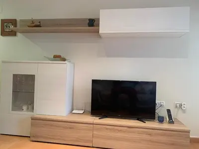 a flat screen tv sitting on top of a wooden entertainment center at Encantador Apartamento dúplex con vistas al mar in Canet de Berenguer
