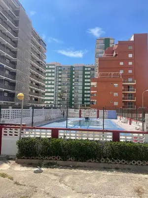 a tennis court in a city with tall buildings at The beach and the sea in front of you in Cullera