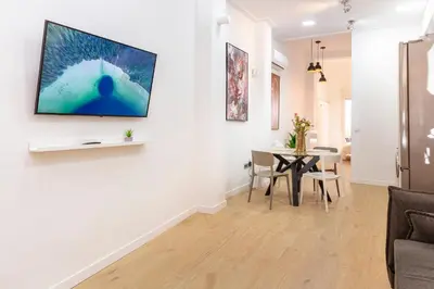 a living room with a table and a tv on a wall at SingularStays Olimpia in Valencia