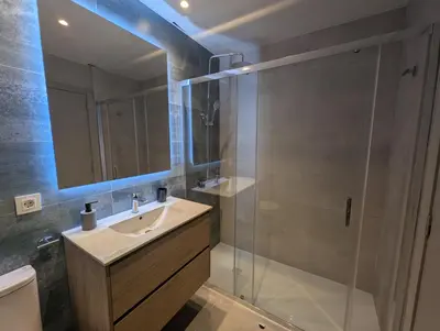 a bathroom with a sink and a glass shower at Port Suites Corporate Living Apartments in Valencia
