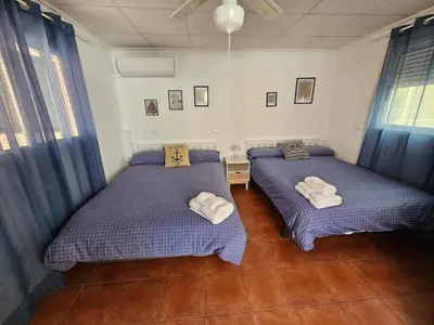 two beds in a room with blue curtains at La Maison du Port in Puerto de Sagunto