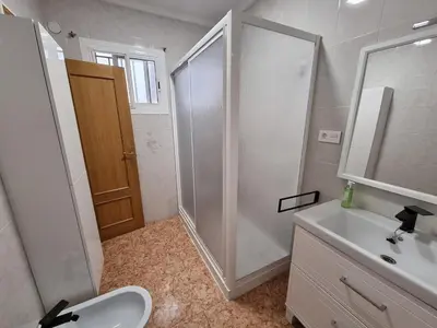 a white bathroom with a shower and a sink at La Maison du Port in Puerto de Sagunto