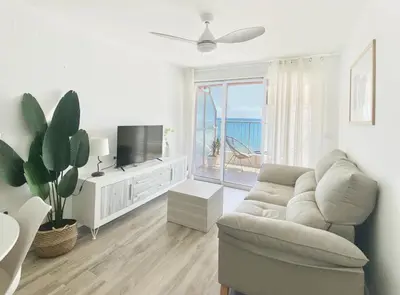 a white living room with a couch and a tv at Beach Apartment in Cullera