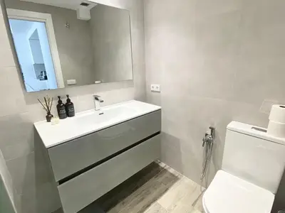 a bathroom with a sink and a toilet and a mirror at Beach Apartment in Cullera