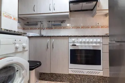 a kitchen with a stove and a washing machine at Global Vacacional, apartamento de una habitación en urbanización con piscina in Canet de Berenguer