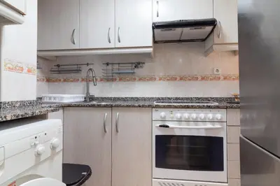 a kitchen with white cabinets and a stove top oven at Global Vacacional, apartamento de una habitación en urbanización con piscina in Canet de Berenguer