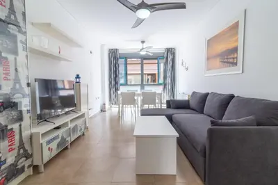 a living room with a couch and a tv at Global Vacacional, Bonito apartamento cerca de la playa in Puerto de Sagunto
