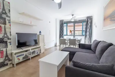 a living room with a couch and a tv at Global Vacacional, Bonito apartamento cerca de la playa in Puerto de Sagunto