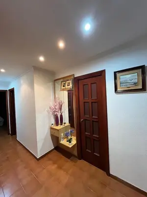 a hallway with a door and a table with flowers at Apartamento Oasis in Cullera