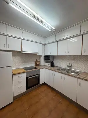 a kitchen with white cabinets and a sink at Apartamento Oasis in Cullera