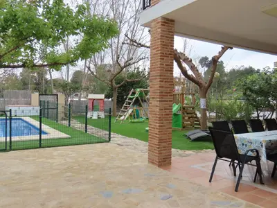 a patio with a table and chairs and a playground at Casa del Prado in Navarrés