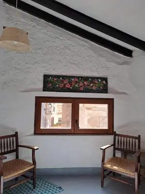 a room with two chairs and a window with flowers at El Cap de Pedra in Calles