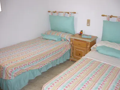 a bedroom with two beds and a wooden dresser at Primer piso de 2 habitaciones en unifamiliar frente al mar in El Brosquil
