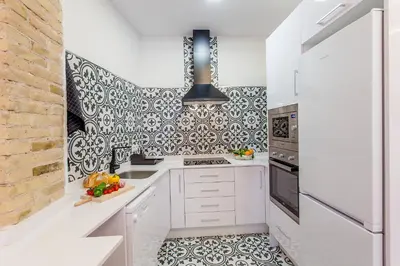 a kitchen with white cabinets and black and white tiles at Apartment Ruzafa Tomasos in Valencia