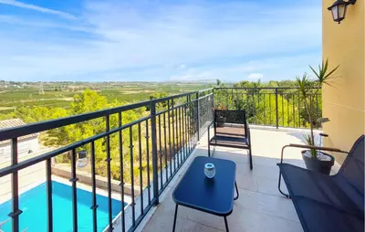 a balcony with a blue table and chairs and a pool at Awesome Home In Turis in Turís