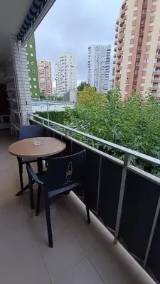 a table and chair on a balcony with a view of a city at Disfruta en familia junto al mar in Playa Pobla de Farnals