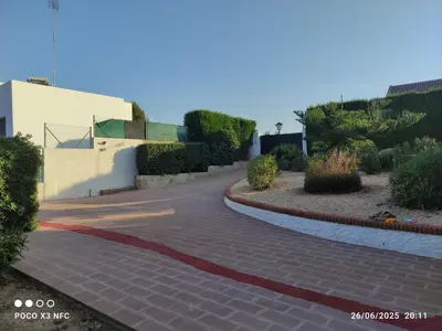 a brick walkway leading to a building with bushes at Chalet en el parque natural de la Calderona in Náquera