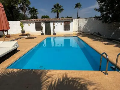 a large blue swimming pool next to a house at Casa Mallaeta in Puebla de Vallbona