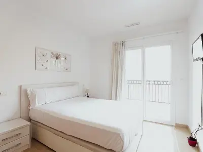 a white bedroom with a white bed and a window at Spectacular views of the sea and the lighthouse in Canet de Berenguer
