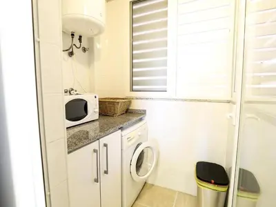 a small bathroom with a washing machine and a microwave at Spectacular views of the sea and the lighthouse in Canet de Berenguer