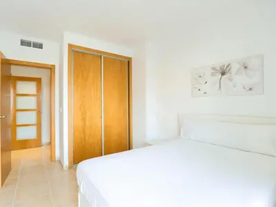 a bedroom with a white bed and a wooden door at Spectacular views of the sea and the lighthouse in Canet de Berenguer