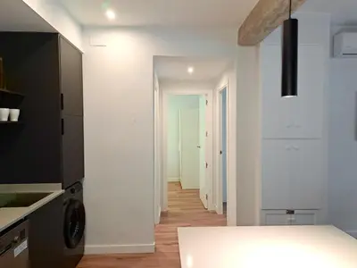 a kitchen with white walls and a hallway with a table at Amazing bright and recently remodeled apartment in Valencia