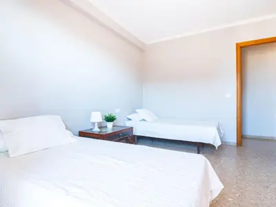 a white bedroom with two beds and a table with a lamp at Apartment Playa Patacona by Interhome in Valencia