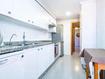 a white kitchen with a sink and a table at Apartment Playa Patacona by Interhome in Valencia