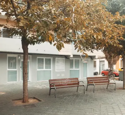 two benches sitting under a tree in front of a building at GO&REST Apartments in Valencia